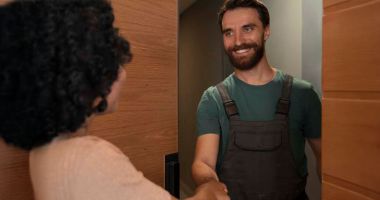 A man and woman shaking hands in a well-lit hallway, symbolizing a professional agreement or greeting.  